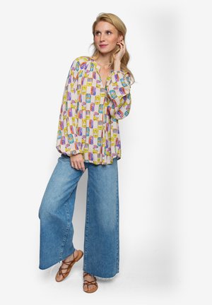 Bluzka z nadrukiem z lekkiego materiału z długimi rękawami, ozdobiona wzorem kolorowych makaroników i słodyczy, zestawiona z szerokimi dżinsowymi spodniami.