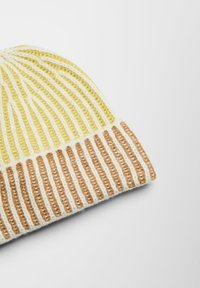 Garen muts in lichtgeel en crèmekleur met bruine accenten. Heeft verticale ribbels en een omgeslagen rand, die getextureerde patronen benadrukt.