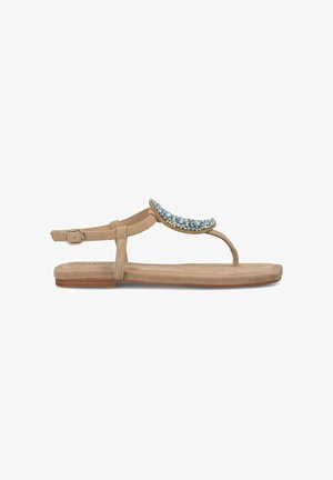 Sandales plates beiges avec un accent décoratif de perles bleues et argentées sur le dessus. Elles sont dotées d'une bride de cheville réglable et d'une semelle lisse.
