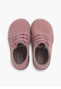 Zapatos de ante rosa claro con puntas redondeadas, cordones texturizados y forro de tela suave. Etiqueta visible en el interior con el nombre de la marca "Pisamonas."