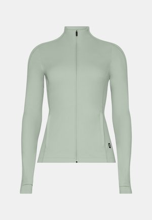 Veste de sport vert clair à fermeture éclair intégrale, manches longues avec trous pour les pouces, dotée d'une petite étiquette noire avec logo près de l'ourlet.