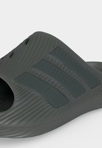 Σανδάλι σε σκούρο γκρι χρώμα τύπου slip-on με υφασμένες γραμμές και τρεις ανυψωμένες ρίγες στην κορυφή, κατασκευασμένο από καλουπωμένο καουτσούκ ή αφρώδες υλικό.