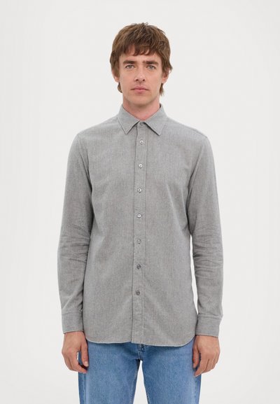 Gray button-up shirt with a collar, long sleeves, and a soft texture. Features subtle patterns and metal buttons, paired with blue jeans.