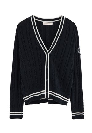 Granatowy kardigan w splot kablowy z białym wykończeniem na kołnierzu, mankietach i krawędzi dolnej, zapinany na guziki, z haftowaną naszywką na lewym rękawie.