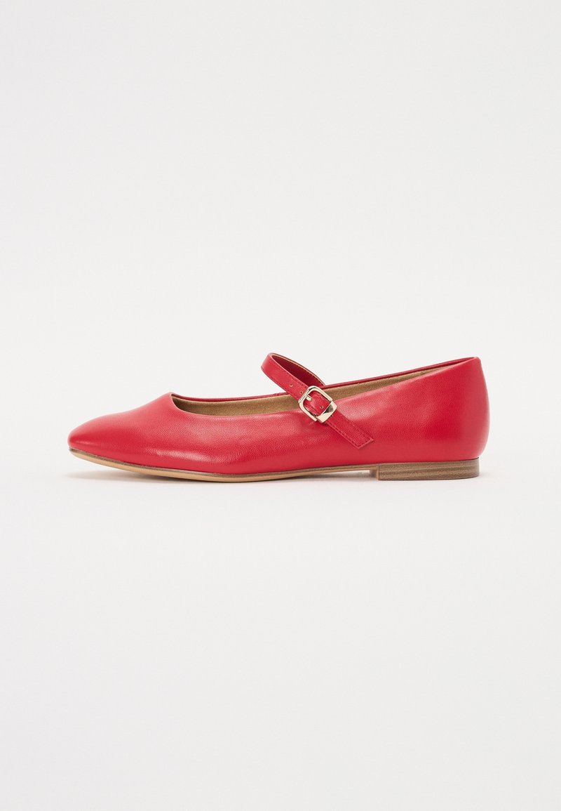 Chaussure plate Mary Jane en cuir rouge avec bout pointu, bride réglable avec boucle métallique et petit talon en bois sur fond blanc.