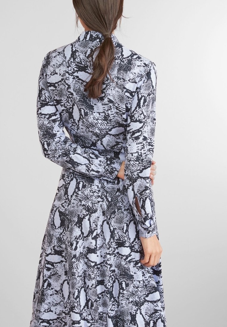 Langärmliges Kleid im Schlangenprint mit Schwarz- und Hellblautönen, mit steigendem Kragen und enganliegenden Ärmeln. Weicher Stoff. 