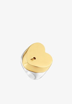 Anillo de plata con una gran parte superior en forma de corazón dorado que presenta un detalle de cerradura en el centro.