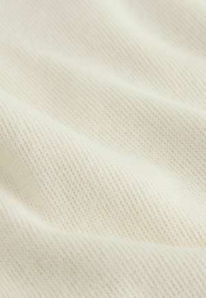 Tissu tricoté texturé en blanc cassé avec une finition douce et lisse. Présente un tissage fin et régulier, mettant en avant sa légèreté et sa respirabilité.