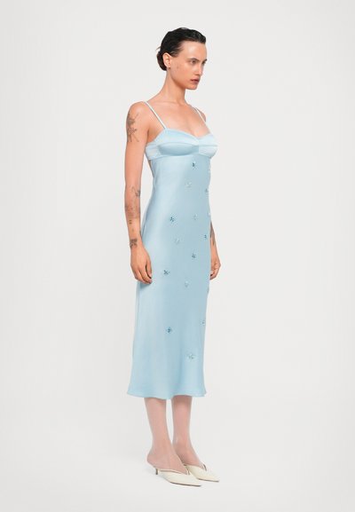 Vestido de satén azul claro con tirantes finos, corsé ajustado y falda fluida. Decorado con pequeños adornos florales azules.