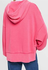 Rosa hoodie med avslappnad passform, ribbad fåll och långärmar. Mjuk tyg med slät textur, minimal detaljer.