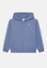 Nike zipsové mikina svetlomodrej farby, vyrobená z mäkkého materiálu, so zipsom vpredu, kapucňou a logom. Biele bočné akcenty s brandingovým textom.