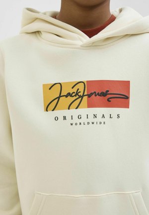 Hoodie crème avec une poche kangourou à l'avant, présentant un design graphique de logo en rouge et jaune. Texture douce et coupe standard.