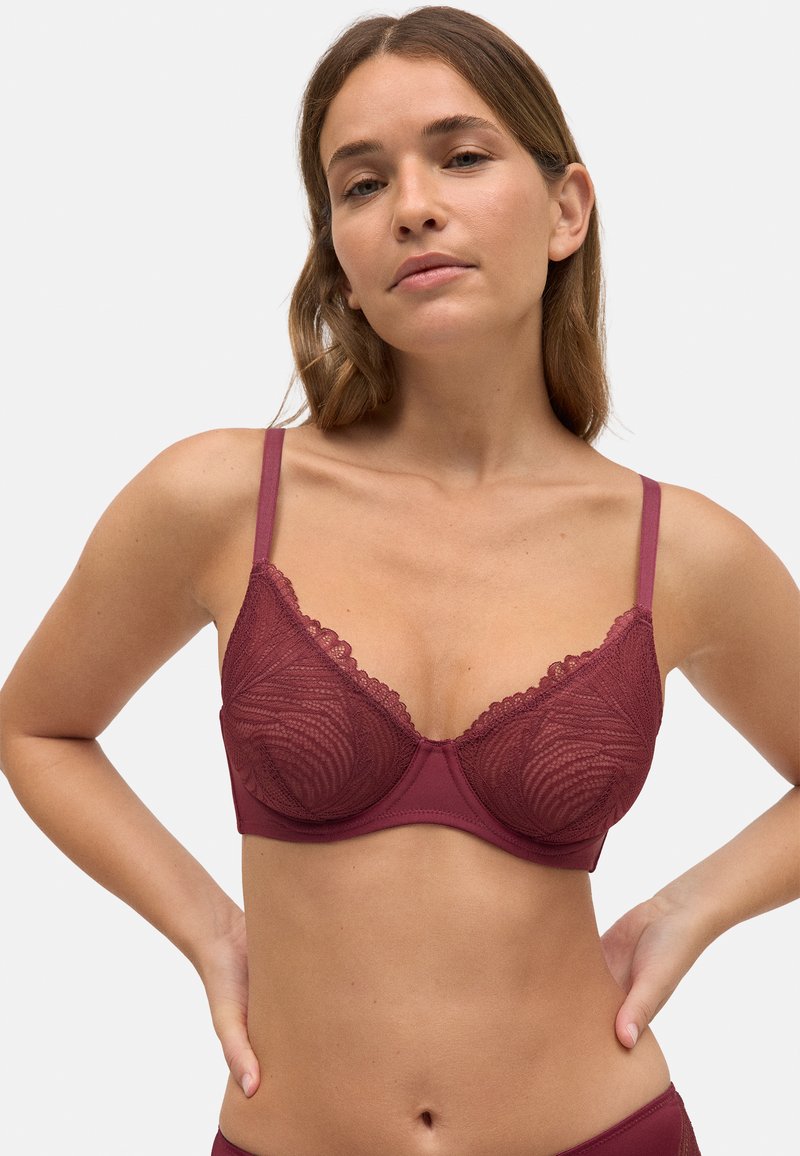 Sostén de encaje burdeos con aros, bordes con picos, copas semitransparentes y tirantes ajustables, que presenta una banda suave y un patrón texturizado.