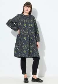 Blumenmuster-Tunika-Kleid in Marineblau mit grünen und weißen Blumen; verfügt über lange Ärmel, einen runden Halsauschnitt und eine lockere A-Linien-Silhouette.