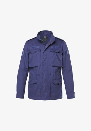 Chaqueta azul marino con cremallera frontal, dos bolsillos en el pecho y dos bolsillos inferiores. Incluye hombreras y parches bordados.