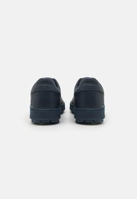Marineblaue Lederschuhe mit abgerundetem Design, strukturierten Oberflächen und Gummisohlen mit kleinen Griffen. "SPHERIC" auf der Rückseite eingraviert.