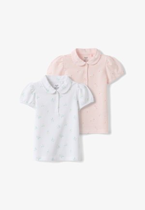 Deux polos enfants à manches courtes avec manches bouffantes, un blanc avec un imprimé floral pastel et un rose clair avec un petit motif floral.