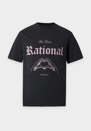 Mand iført en sort t-shirt med teksten "Far From Rational" og hånd-hjerte grafik, brede beige bukser og sorte sneakers, står mod en hvid baggrund.