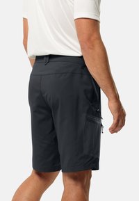 Mannentrije grijs short in lichte stof, met een zijrits pocket, een getailleerde pasvorm en een soepele textuur, zichtbaar vanaf de achterkant.