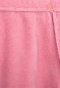 Rosa, weicher Stoff mit samtiger Textur, ausgestattet mit einem glatten, elastischen Bund und einem genähten Rand. Ein kleines Logo ist nahe der Oberseite sichtbar.