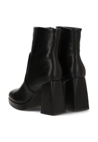 Botas de tobillo negras de cuero suave con un alto tacón bloque y cremalleras laterales. El diseño presenta una silueta minimalista sin acentos adicionales.