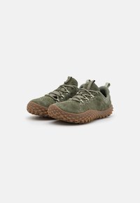 Zapatillas de ante verde con una suela de goma marrón texturizada. Incluyen cordones redondos, una tira en el talón y detalles perforados en la parte superior.