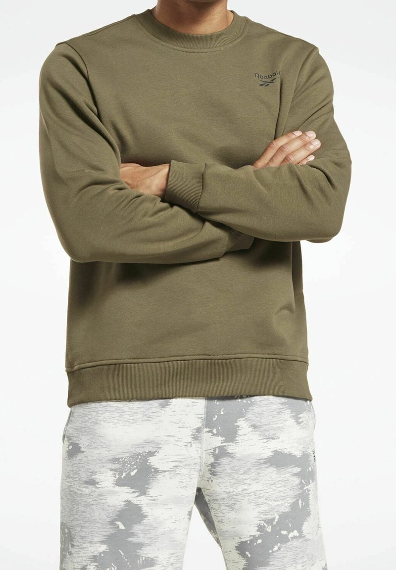 Olivgrön sweatshirt i mjukt tyg, med rund halsringning, ribbade ärmslut och nederkant, samt en liten svart logotyp på vänster bröst.