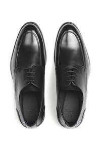 Zwarte leren schoenen met een gladde afwerking, ronde neus en klassiek vetersluiting ontwerp. Voorzien van stikdetails langs de neuskap en de zijkanten.