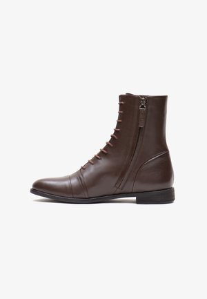 Brauner Leder-Ankle-Boot mit runder Zehenpartie, vornem Schnürverschluss und seitlichem Reißverschluss. Besitzt eine glatte Oberfläche und minimale Nahtdetails. Flache Sohle.