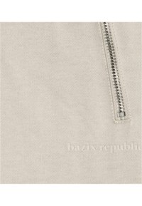 Felpa beige chiaro con una texture liscia, caratterizzata da una zip argentata e testo del marchio in rilievo, che mette in mostra un design minimalista.