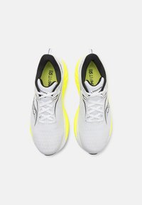 Weiße Sneakers mit einer strukturierten Oberseite, schwarzen Akzenten und neongelben Sohlen. Verfügt über Schnürsenkel und einen gepolsterten Kragen für Komfort.