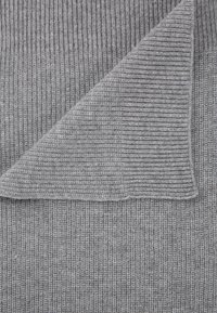 Grau gestrickter Stoff mit gerippter Textur, an der Ecke gefaltet, zeigt den weichen Stoff und das gleichmäßige Muster über das gesamte Material.