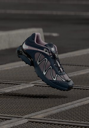 Granatowe i różowe buty sportowe z siateczkową cholewką, refleksyjnymi akcentami i elastyczną podeszwą. Posiadają system szybkiego sznurowania oraz wyraźny wzór przyczepności.