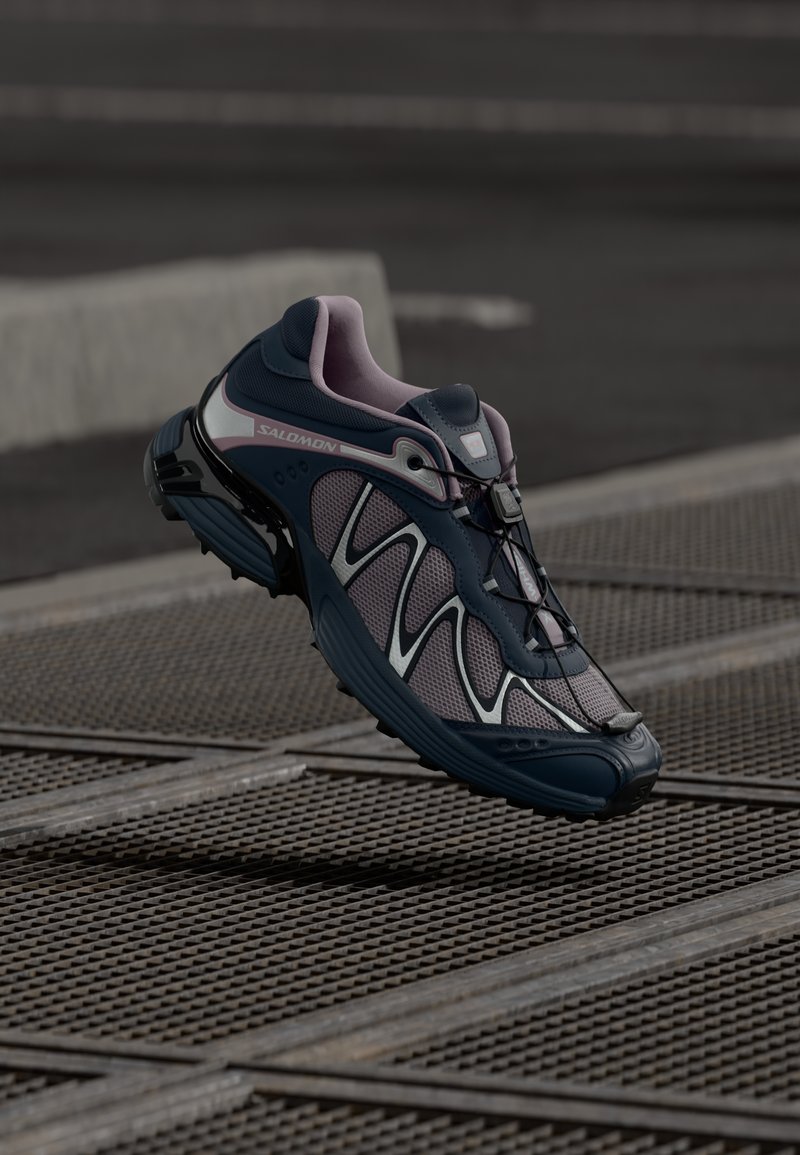 Zapatilla deportiva en azul marino y rosa con parte superior de malla, acentos reflectantes y suela flexible. Cuenta con un sistema de cordones rápido y un patrón de agarre prominente.