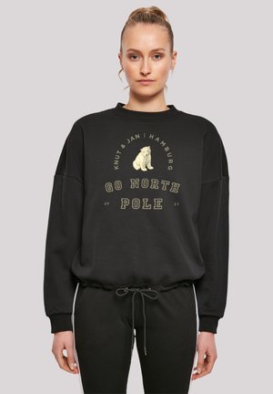 Schwarzes Sweatshirt mit Rundhalsausschnitt und gerippten Bündchen, versehen mit einem Polarbären-Graphic und dem Text "GO NORTH POLE" in Creme und Gold.
