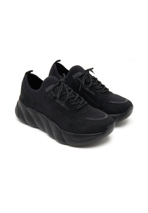 Black sneakers with a textured fabric and smooth accents, featuring a chunky sole with wave-like design and standard lacing system.