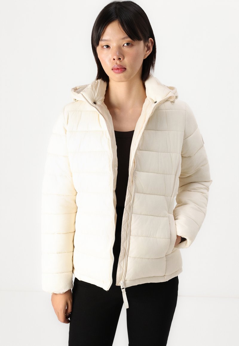 Giubbotto imbottito in off-white con cappuccio, design trapuntato, chiusura frontale con zip e tasche laterali. Tessuto morbido e finitura leggermente lucida.