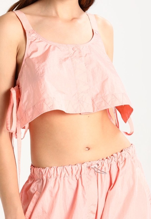 Lichtroze crop top met spaghettibandjes, met een knoopsluiting en een textuurpatroon. Lichte stof met een losse pasvorm.