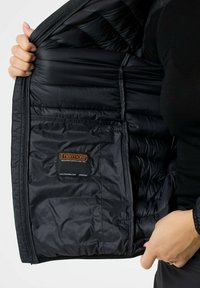 Black padded jacket interior with quilted texture. Features a pocket and a label indicating "Thermore" insulation. Smooth, lightweight material.