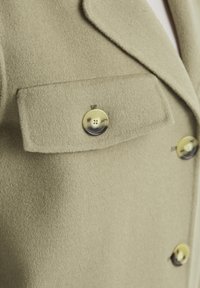 Olivgrüner Wollmix-Mantel mit großen goldenen Knöpfen, einem maßgeschneiderten Revers und einer Brusttasche für praktische Details.