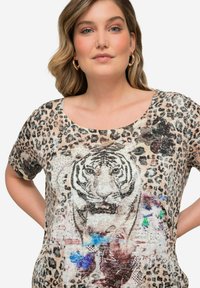 Camiseta de estampado de leopardo con un gráfico central de tigre, adornado con acentos en azul y rojo, cuello redondo y mangas cortas.