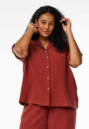 Rust-colored, textured, button-up shirt with a notched collar and short sleeves, featuring rounded hem and front placket.