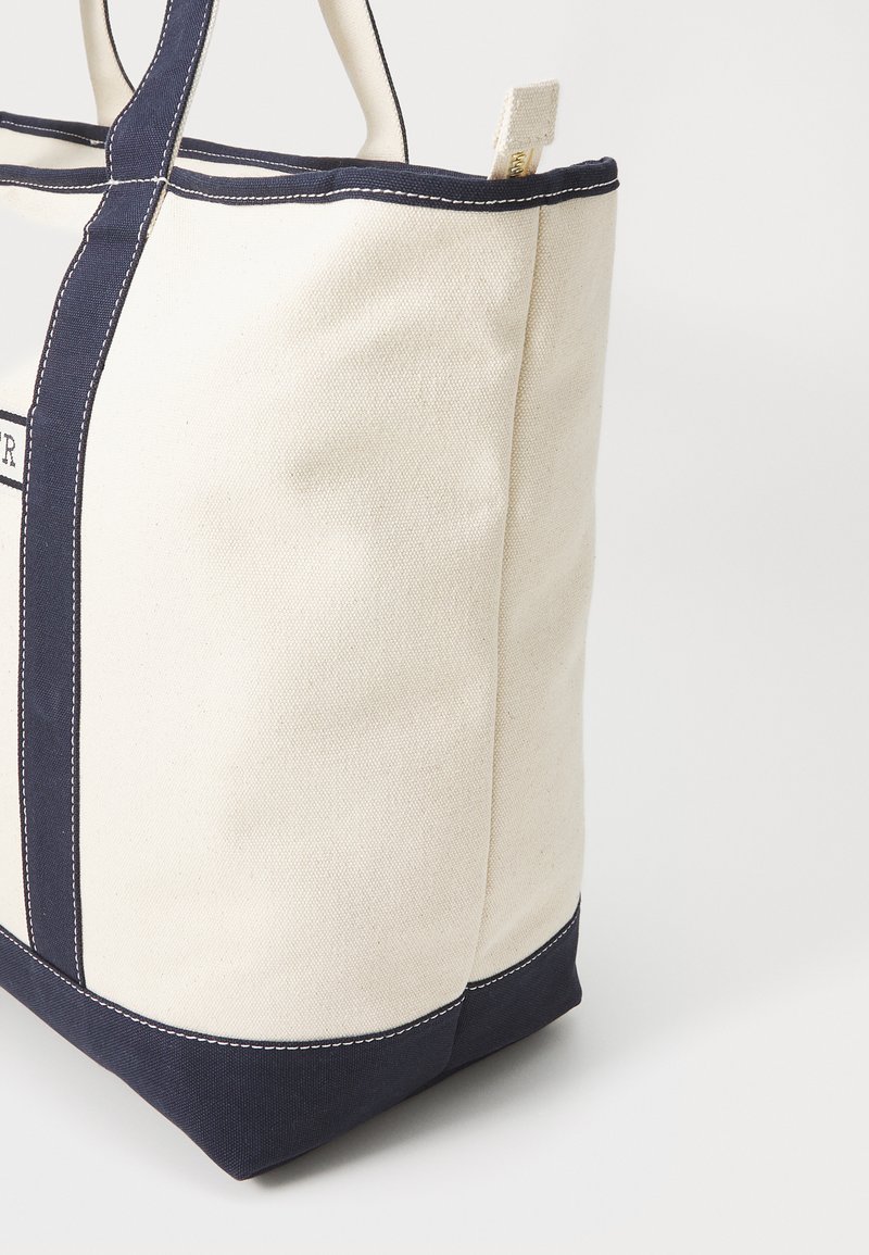 Torba płócienna w kremowym kolorze z granatowymi akcentami. Posiada mocne uchwyty oraz kontrastowe przemyślenia. Kwadratowy kształt z wzmocnioną podstawą.
