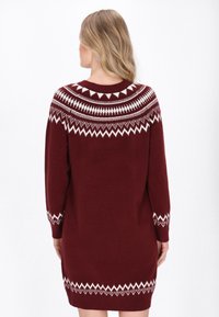 Bordeaux trui jurk met een ronde halslijn, lange mouwen en een wit fair isle patroon langs de schouderpartij en manchetten. Zachte gebreide textuur.
