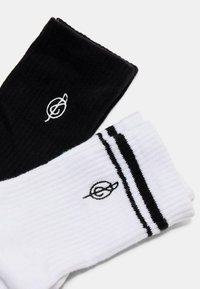 Sorte og hvide ribbede sokker med logo broderi; sort sok solid, hvid sok med to sorte striber nær toppen.