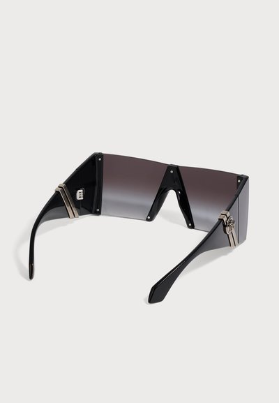Lunettes de soleil futuristes enveloppantes noires avec une seule lentille teintée foncée et des accents décoratifs argentés sur les branches.