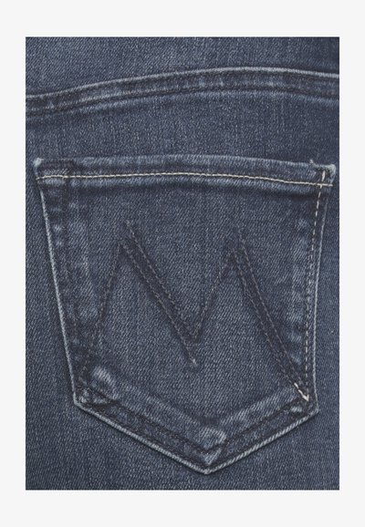 Il tessuto in denim blu scuro presenta una tasca posteriore con una patta triangolare e un motivo di cucitura a zigzag in contrasto.