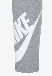 Calções atléticos cinzentos com o logótipo Nike em branco e gráfico do swoosh; confeccionados em tecido suave e texturizado; apresentam um corte e bainha padrão.