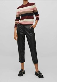 Gestreepte trui in bordeauxrood, crème en bruin met een ronde hals; gecombineerd met zwarte cropped broek van nepleer; zwarte loafers maken de outfit af.