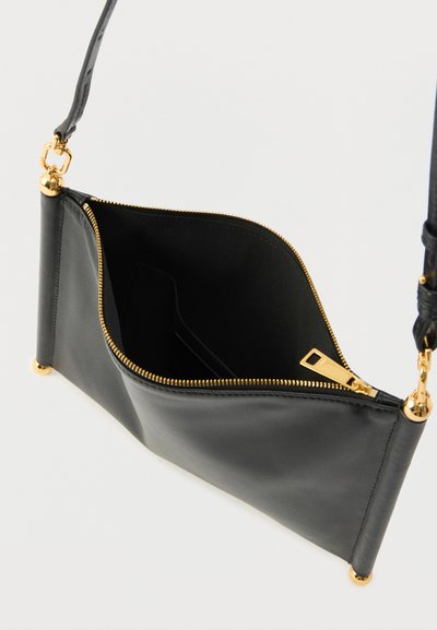 Pochette en cuir noir avec une fermeture éclair dorée, une texture lisse et une forme mince. Présente des coins arrondis et des accents métalliques dorés.